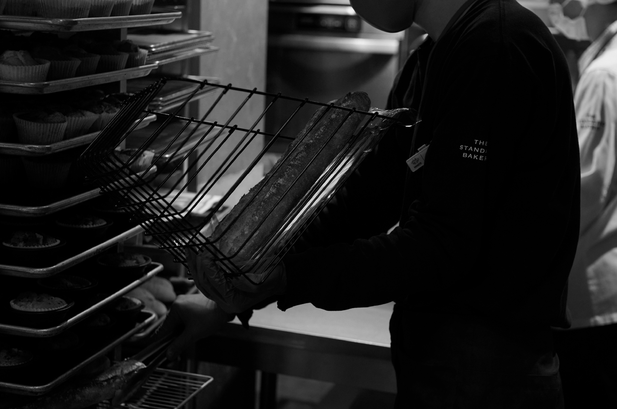 焼きたてのパンをラックに並べるパン職人